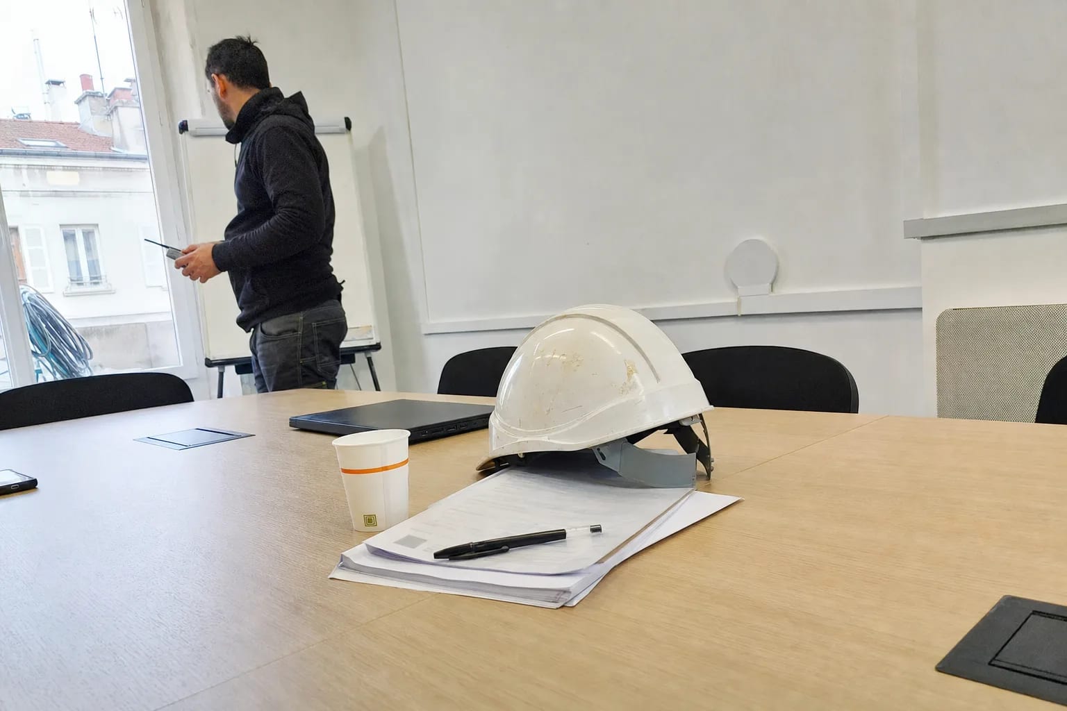 Casque de chantier posé sur des documents contractuels de construction