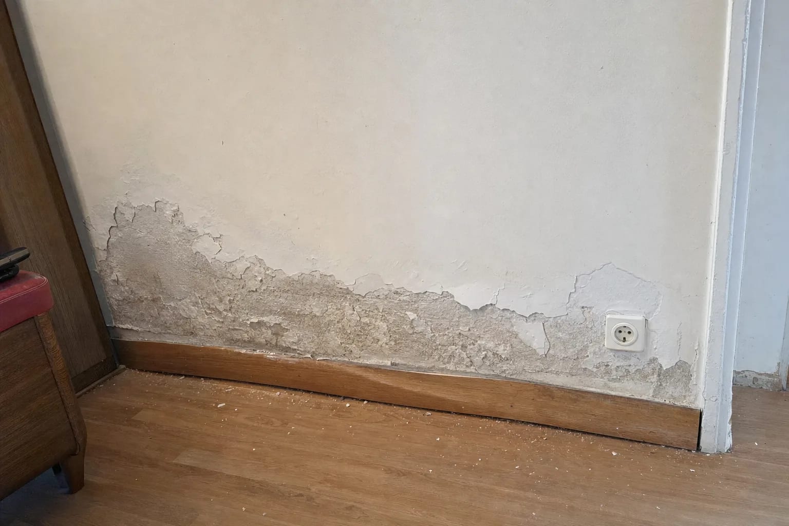 Pied de mur intérieur rongé par le salpêtre, peinture qui s'écaille