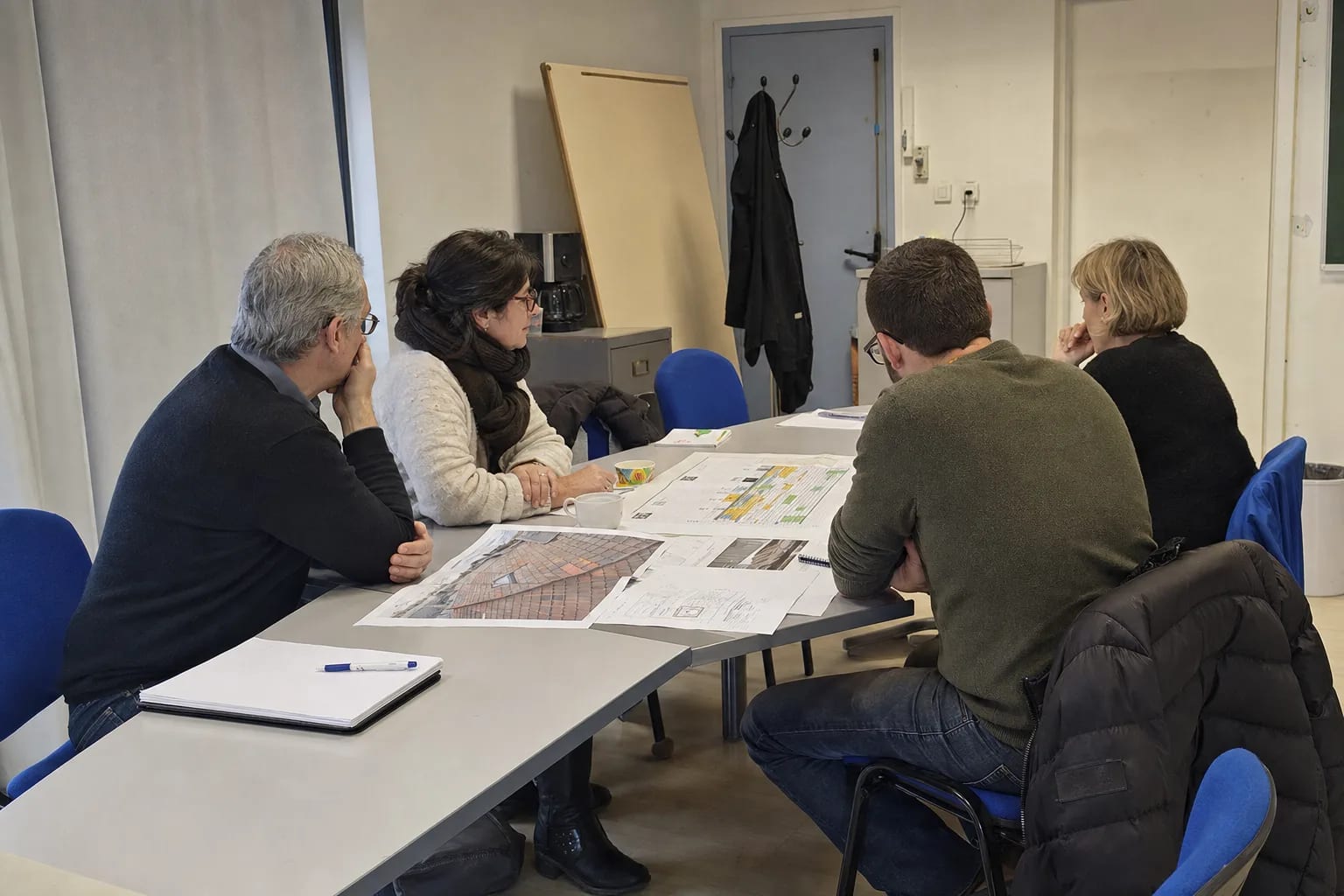Conseil syndical examinant un planning de travaux et des photos de toiture