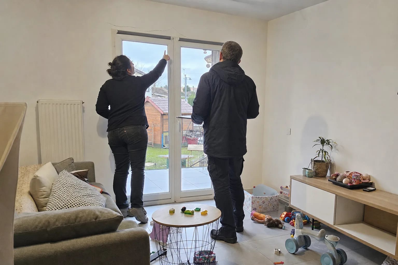 Propriétaire montrant une fissure à un expert bâtiment dans son salon