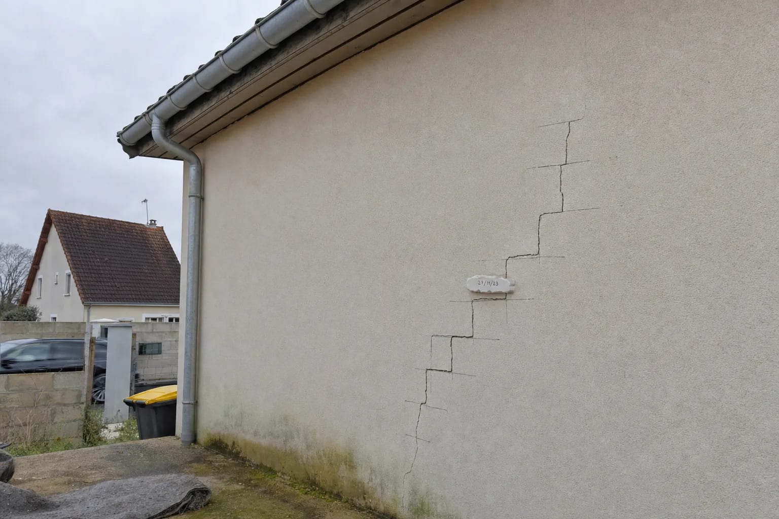 Fissure en escalier sur la façade enduite d'un pavillon, suivie au crayon